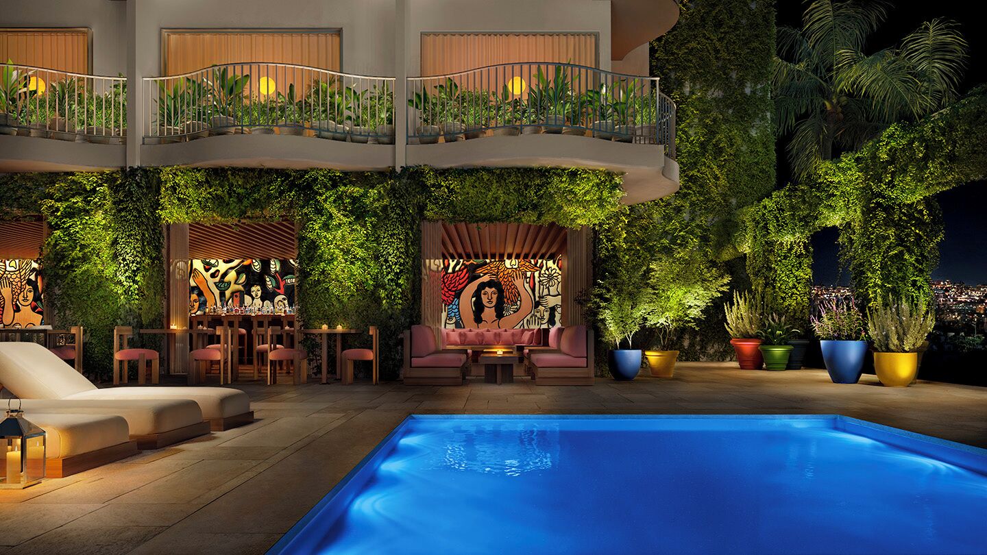 An indoor pool area with a lounge, seating, and a balcony with plants.