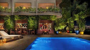 An indoor pool area with a lounge, seating, and a balcony with plants. - PUBLIC West Hollywood (West Hollywood)