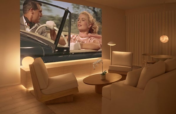 A modern living room with a flat-screen TV, comfortable seating, and a small table with a plant. - PUBLIC West Hollywood (West Hollywood)