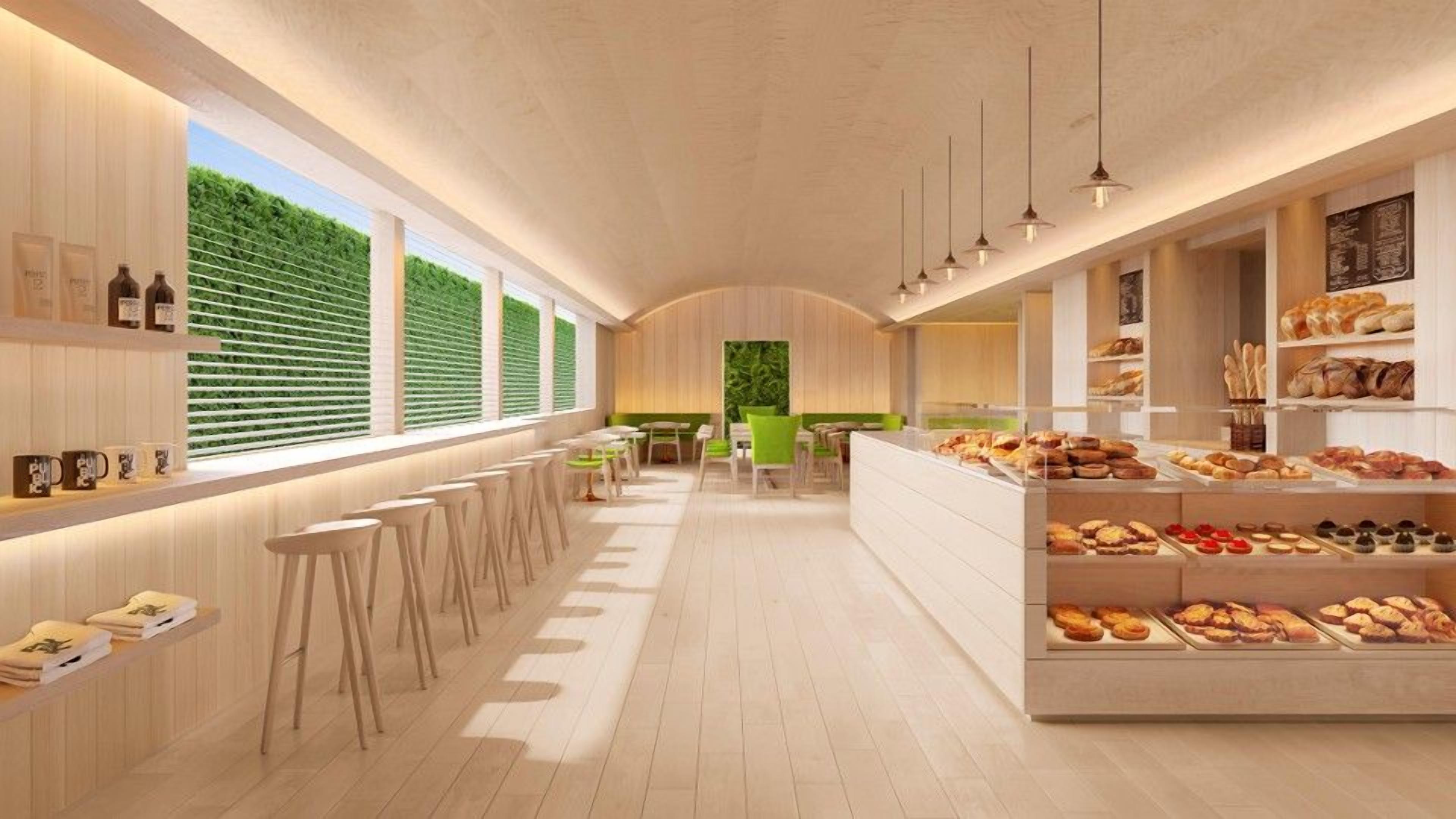 L’intérieur d’un café moderne présente un long comptoir, des tabourets de bar et une variété de produits de boulangerie exposés.