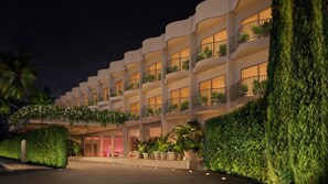A multi-story hotel with balconies, a well-lit entrance, and a manicured garden. - PUBLIC West Hollywood (West Hollywood)