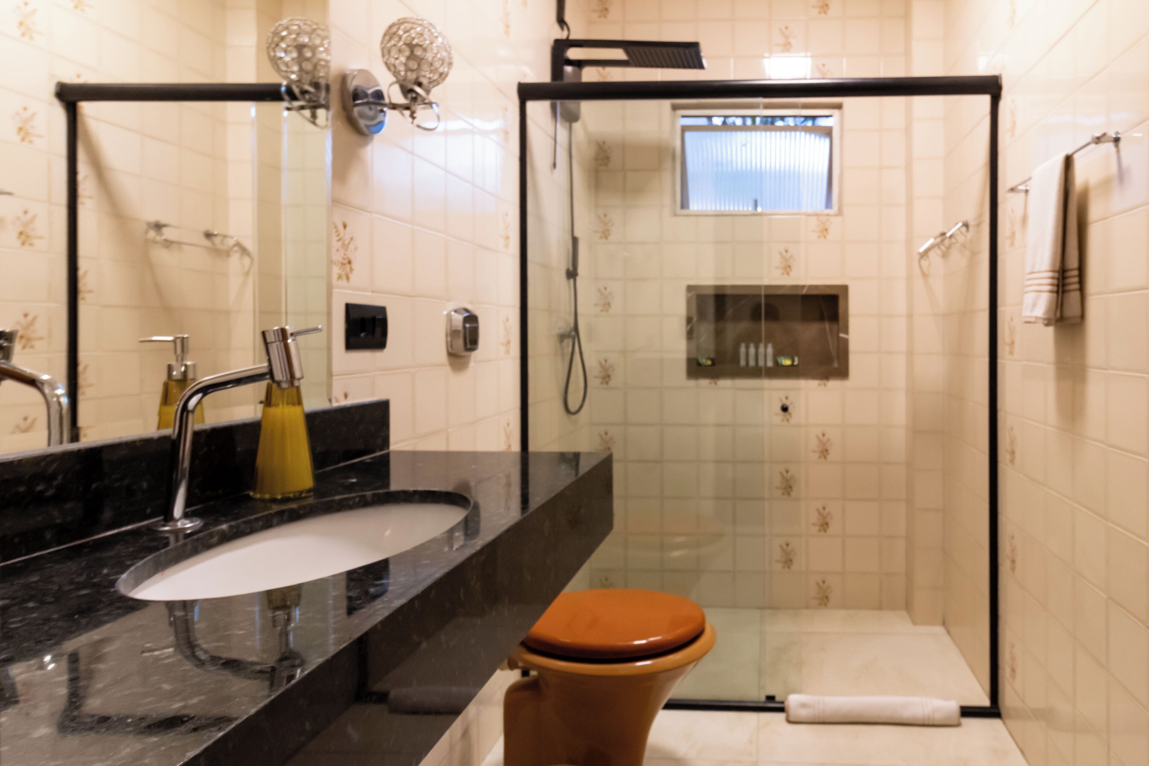 A bathroom with a glass-enclosed shower, a sink with a mirror, and a toilet.