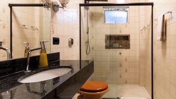 A bathroom with a glass-enclosed shower, a sink with a mirror, and a toilet.