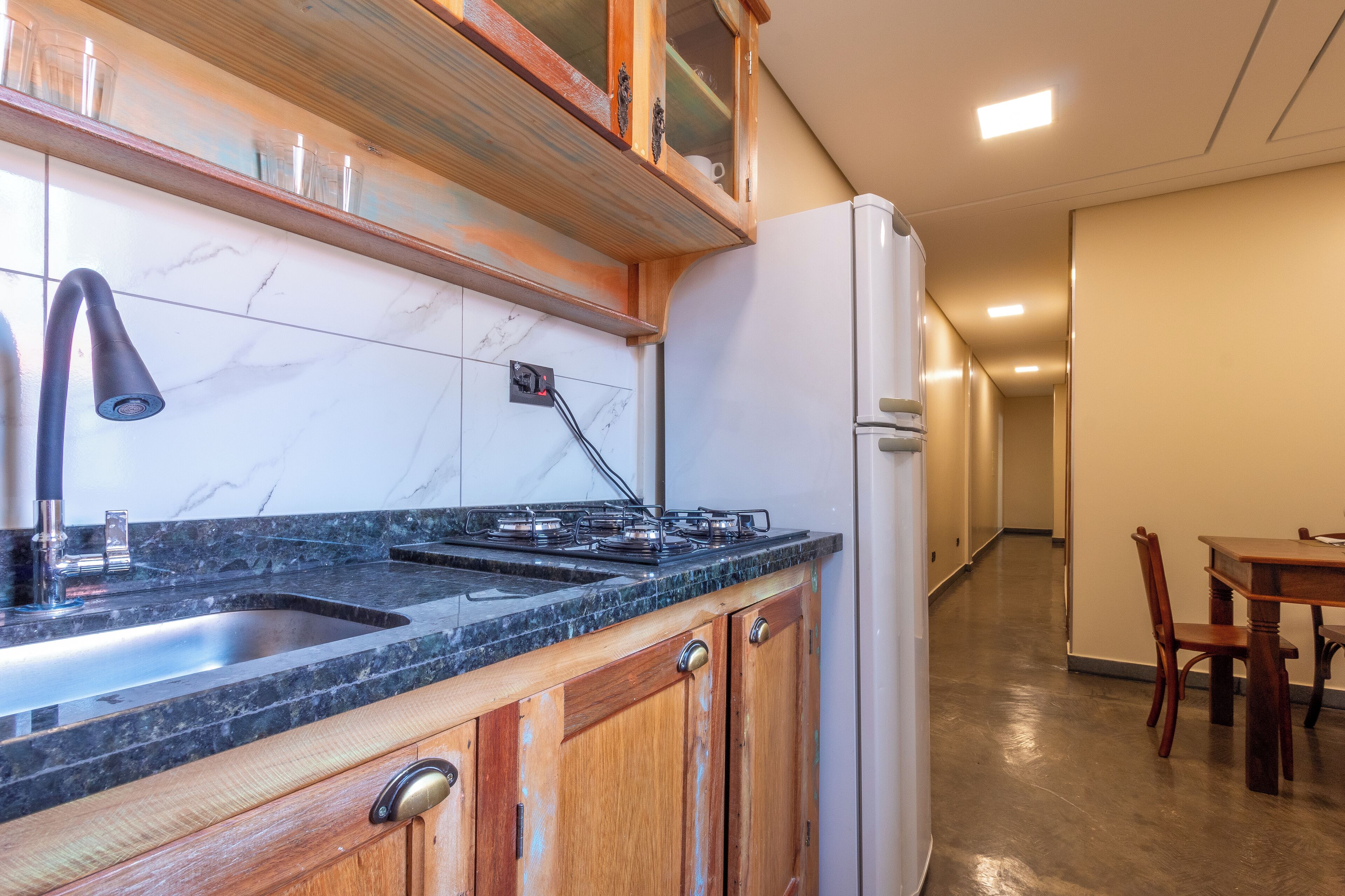 A kitchen with a marble backsplash, wooden cabinets, a stainless steel sink, and a built-in stove.