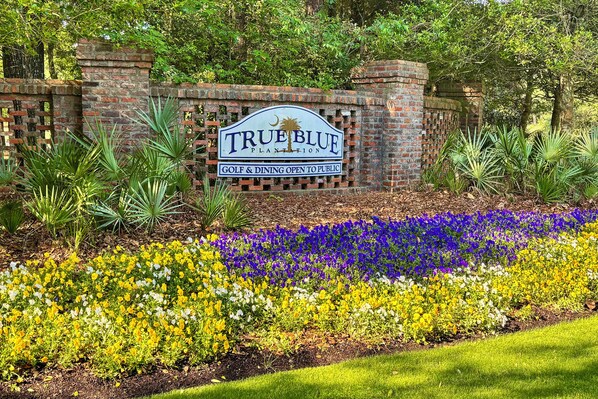 Placa para True Blue Plantation com área de golfe e restaurante aberta ao público.