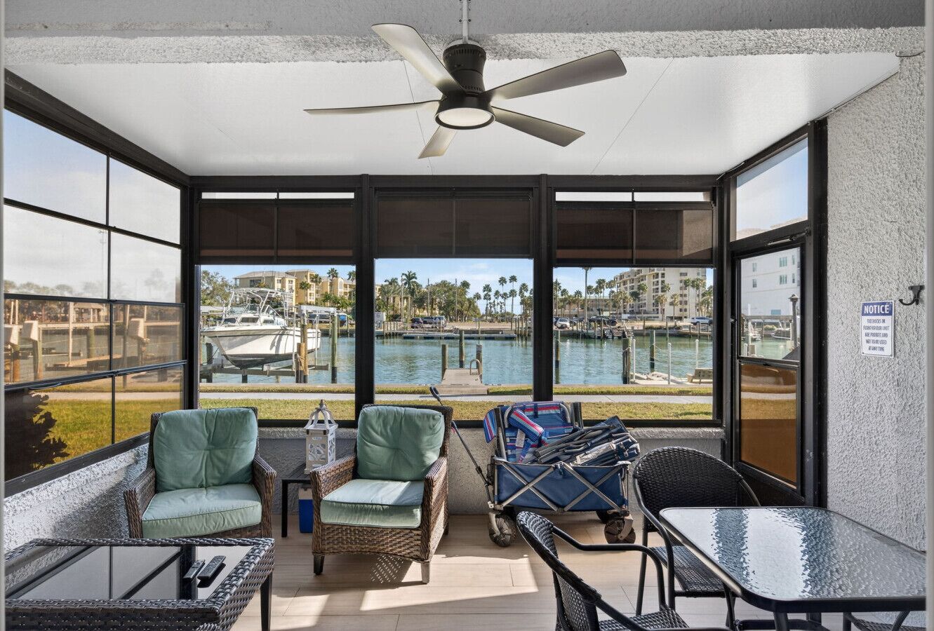 Ein Balkon mit Korbmöbeln, einem Deckenventilator und Blick auf eine Marina.