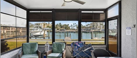 A balcony with wicker furniture, a ceiling fan, and a view of a marina.