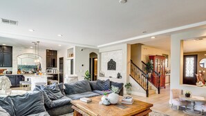 Ein geräumiges Wohnzimmer mit einem großen, grauen Ecksofa, einem Holztisch und einer Treppe, die in den oberen Bereich führt.