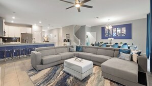 A modern living room with a sectional sofa, a coffee table, and a dining area in the background. - Game Room, Theater & Pool! Ultimate Disney Oasis (Davenport)