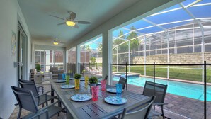 An outdoor patio with a table set for dining, a pool, and a greenhouse structure in the background. - Game Room, Theater & Pool! Ultimate Disney Oasis (Davenport)