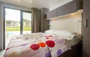 A modern hotel room with a large bed, a sliding glass door to the outside, and a built-in headboard. - Lovely (sta)caravan in Vabriga (Vabriga)