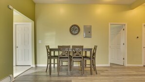 A dining area with a wooden table and chairs, a wall clock, and a light switch. - Easy NYC Access: Updated Apt Near Parks & Bay! (Mt Vernon)