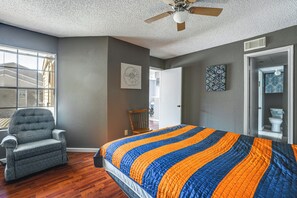 A bedroom with a large bed, a chair, a ceiling fan, and a door leading to a bathroom. - 3 Mi to Houston Medical Center: Extended Stay (Houston)