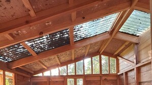 A cabin with two wooden beds, a stone wall, and large windows.