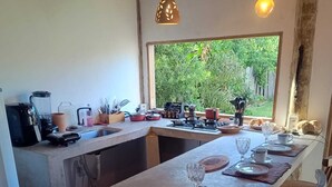 Ett kök med en lång köksö, en diskho och ett fönster med utsikt över grönområden.