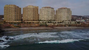 Ein Küstenhotel mit mehreren Hochhäusern, direkt am Strand und einer felsigen Küstenlinie.