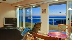 Ein Balkon mit Blick auf den Ozean, einem Fernseher und Sitzgelegenheiten.