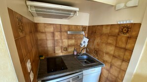 Een compacte keuken met een inbouwvaatwasser, een spoelbak en een fornuis.