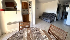 A compact living space with a kitchenette, a sofa, and a dining table with chairs. - Apartment for 4 with parking near beach (Argelès-sur-Mer)