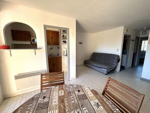 A compact living space with a kitchenette, a sofa, and a dining table with chairs. - Apartment for 4 with parking near beach (Argelès-sur-Mer)