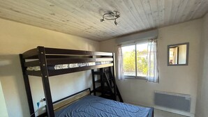 A bunk bed room with a window, a radiator, and a mirror on the wall. - Apartment for 4 with parking near beach (Argelès-sur-Mer)