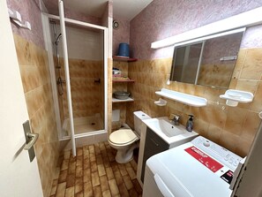 A compact bathroom with a shower, toilet, sink, and a washing machine. - Beachfront Apartment with Parking (Argelès-sur-Mer)