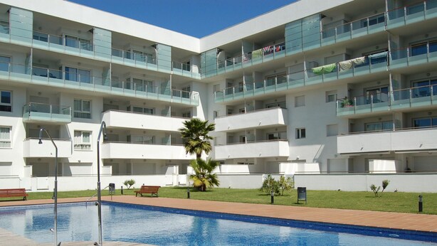 A modern hotel with a swimming pool, multiple balconies, and a well-maintained lawn. - Bright Apartment with Terrace and Parking in Santa Margarita (Roses)