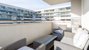 A balcony with wicker furniture, a table, and a view of a multi-story building with balconies. - Bright Apartment with Terrace and Parking in Santa Margarita (Roses)