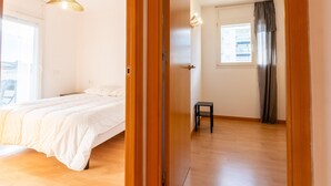 A bedroom with a bed, a small stool, a window with curtains, and a door. - Bright Apartment with Terrace and Parking in Santa Margarita (Roses)
