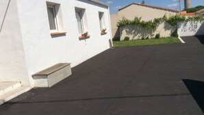Ein Gebäude mit drei Fenstern, einer kleinen Veranda und einer befestigten Fläche.