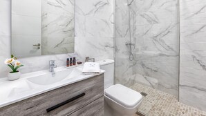 Ein modernes Badezimmer mit Marmorwaschbecken, einem Holzwaschtisch, einer Toilette und einer Duschkabine aus Glas.