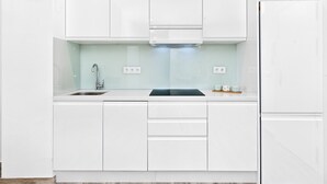 Eine moderne Küche mit weißen Schränken, einer Edelstahl-Spüle und einem eingebauten Backofen.