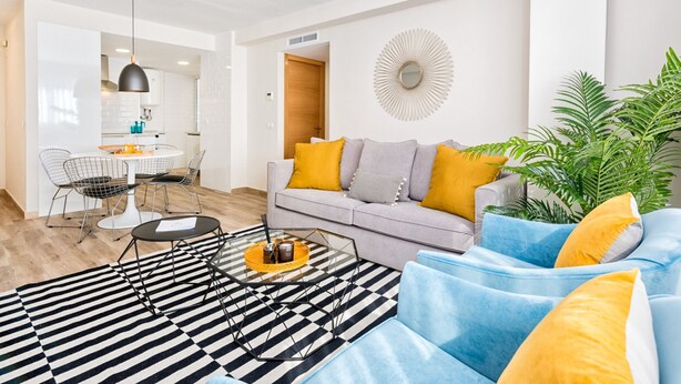 A modern living room with a sofa, a coffee table, and a dining area with chairs and a table. - Spacious 5-Bedroom Apartment near Guadalmedina River, Málaga (Málaga)