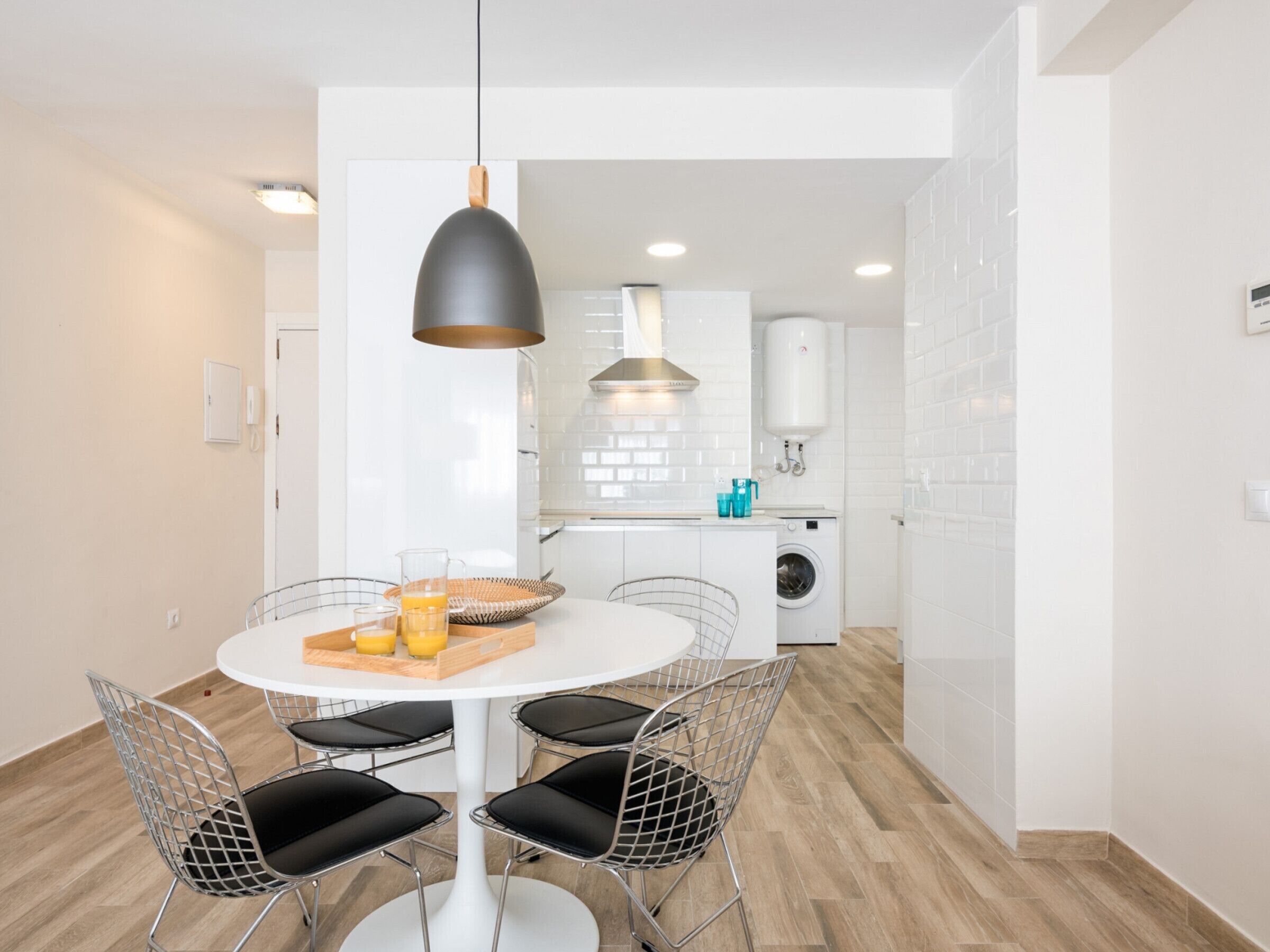 Una cocina moderna con armarios blancos, lavadora integrada y calentador de agua.