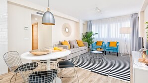 A modern living room with a sofa, two armchairs, a dining table with chairs, and a large window with curtains. - Spacious 5-Bedroom Apartment near Guadalmedina River, Málaga (Málaga)