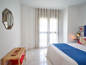 Ein Hotelzimmer mit Bett, Nachttisch, Spiegel, Fenster mit Vorhängen und einer Lampe.