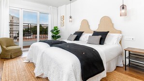 A modern bedroom with a large bed, a balcony, and a view of buildings. - Elegant 3-Bedroom Apartment in Malaga City Center with Terrace (Málaga)