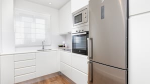 A modern kitchen with white cabinetry, a stainless steel refrigerator, a microwave, and an oven. - Elegant 3-Bedroom Apartment in Malaga City Center with Terrace (Málaga)