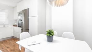 A modern kitchen with white cabinetry, a stainless steel refrigerator, and a wooden floor. - Elegant 3-Bedroom Apartment in Malaga City Center with Terrace (Málaga)