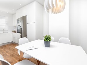 Eine moderne Küche mit weißen Schränken, einem Edelstahlkühlschrank und Holzboden.