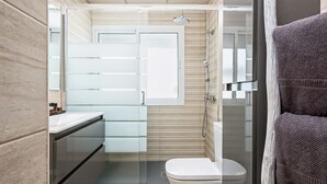 Ein modernes Badezimmer mit einer Duschkabine, einer Toilette und einem Waschtisch mit Spiegel.