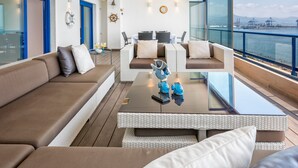 A modern outdoor seating area with a view of the sea, featuring a sofa, chairs, and a coffee table. - Seafront penthouse with WiFi, parking, and air conditioning in Malaga (Málaga)