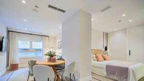 Ein modernes Hotelzimmer mit Essbereich, einem Bett mit Kopfteil und einem großen Fenster.