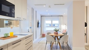 Eine moderne Küche mit eingebauter Mikrowelle, einem Holzespeisetisch mit vier Stühlen und einem großen Fenster mit Vorhängen.