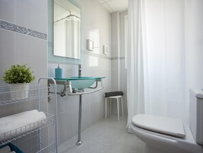 Ein modernes Badezimmer mit Waschbecken aus Glas, einer weißen Toilette und einer Duschkabine.