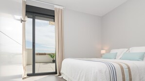 A modern hotel room with a large bed, a balcony with a potted plant, and a view of the sky. - Chic 3-bedroom apartment with terrace, Wifi, and parking in Malaga (Málaga)
