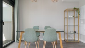 A modern dining area with a glass table, four teal chairs, and two pendant lights. - Chic 3-bedroom apartment with terrace, Wifi, and parking in Malaga (Málaga)