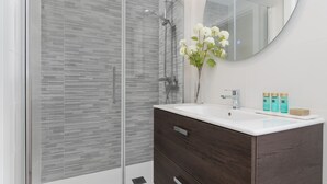 A modern bathroom with a glass shower enclosure, a wooden vanity, and a mirror. - Chic 3-bedroom apartment with terrace, Wifi, and parking in Malaga (Málaga)