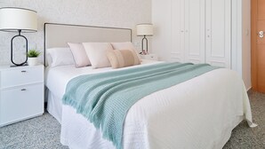 Een netjes opgemaakt slaapkamer met een bed, twee nachtkastjes en een kledingkast.