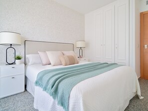 Ein ordentlich eingerichtetes Schlafzimmer mit einem Bett, zwei Nachttischen und einem Kleiderschrank.